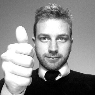 A man is holding his thumb up in an approval gesture in a black and white photo