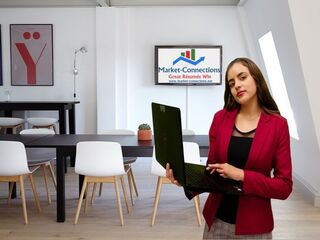Photo of a lady with a laptop in an office. There is also a logo from https://www.market-connections.net